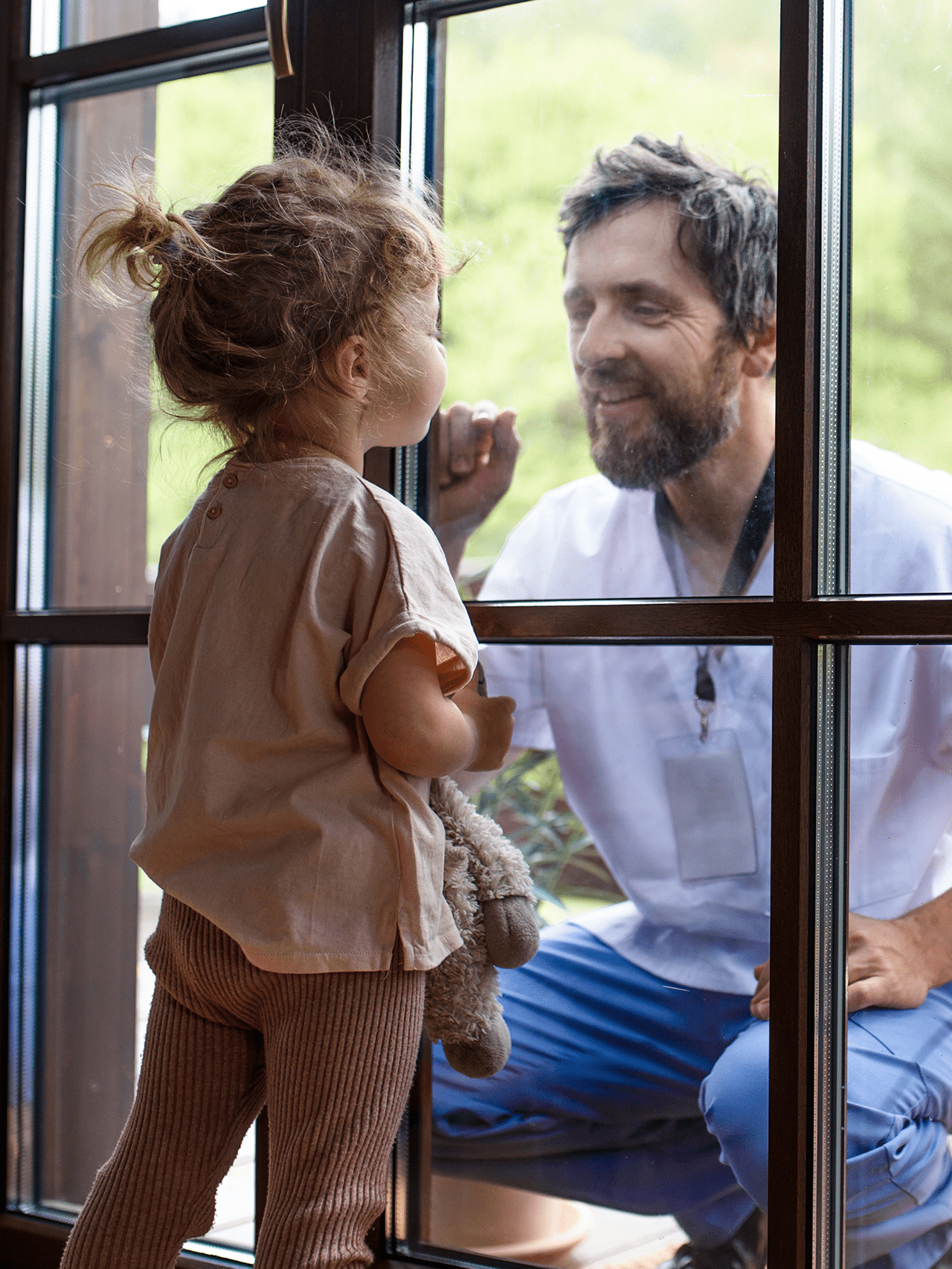 Een kind kijkt door het raam naar een man